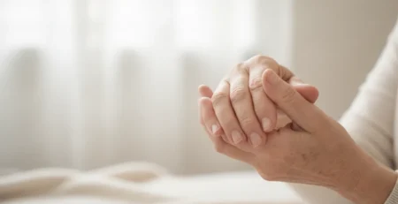 Persoană în vârstă care își masează mâinile afectate de dureri articulare.