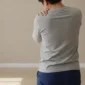 Persoană care își ține umărul dureros cu mâna, într-o cameră luminoasă